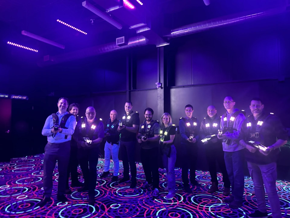 OKIOK colleagues in laser tag vests in a neon-lit arena.