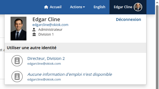 Le menu de profil ouvert en haut à droite: la photo, le nom, le courriel, le rôle et la division de l’utilisateur connecté, un lien de déconnexion, et dessous une liste permettant d’utiliser une autre identité parmi celles que détient la même personne.